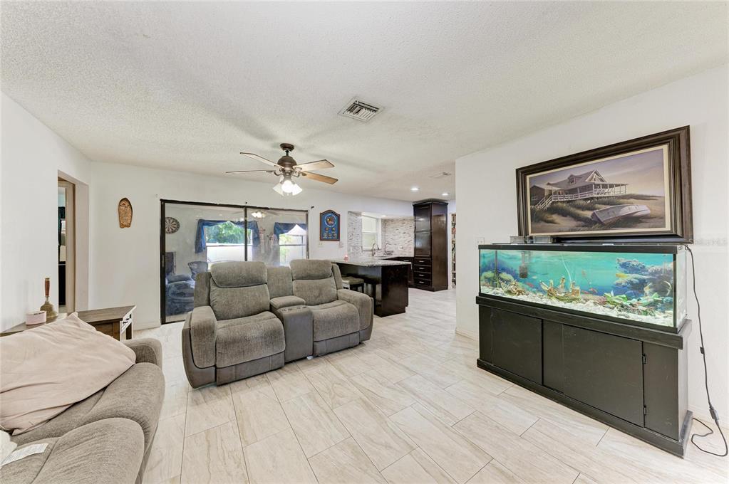 A living room with tile floors, a gray sofa, and a large fish tank — 1520 SUNNYHILLS DRIVE, BRANDON, FL