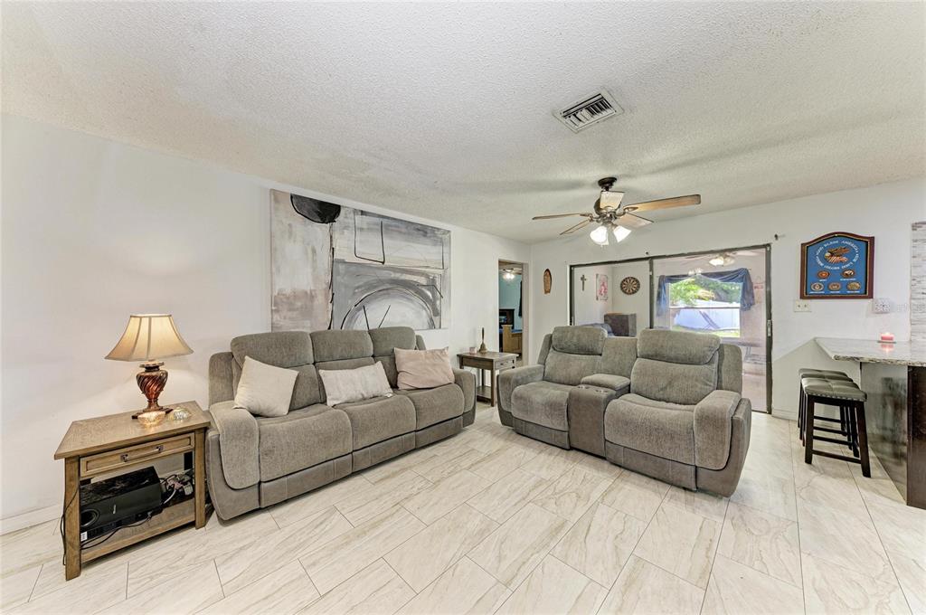A living room features gray sofas, a side table, and light-colored tile flooring — 1520 SUNNYHILLS DRIVE, BRANDON, FL