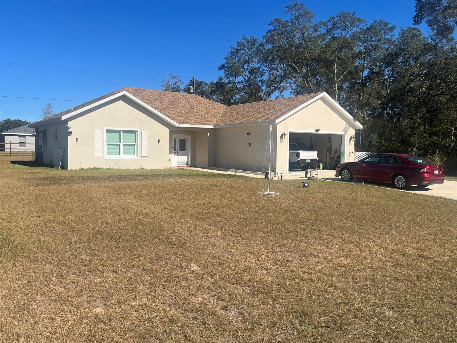 A single-story tan house with a brown shingled roof and an attached two-car garage — 4009 SW 133rd Loop, Ocala FL 34473, OCALA, FL