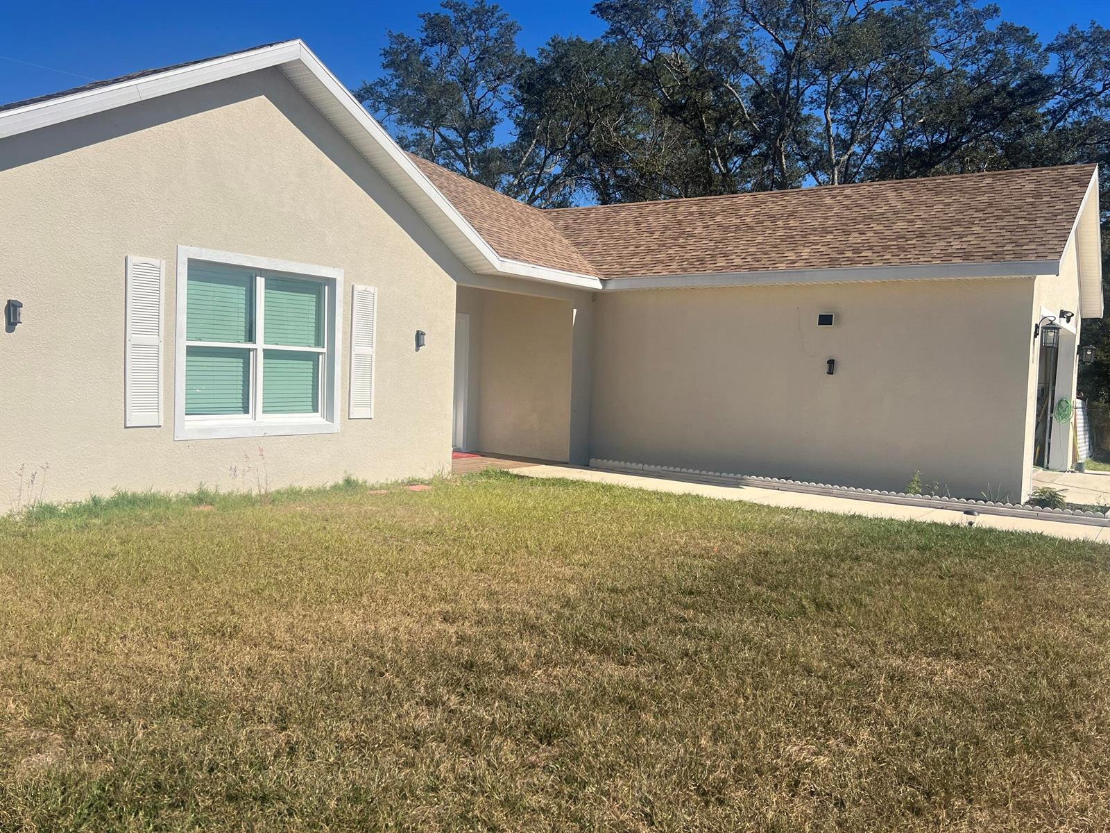 A single-story house with beige stucco siding, a brown shingled roof, and a front lawn — 4009 SW 133rd Loop, Ocala FL 34473, OCALA, FL
