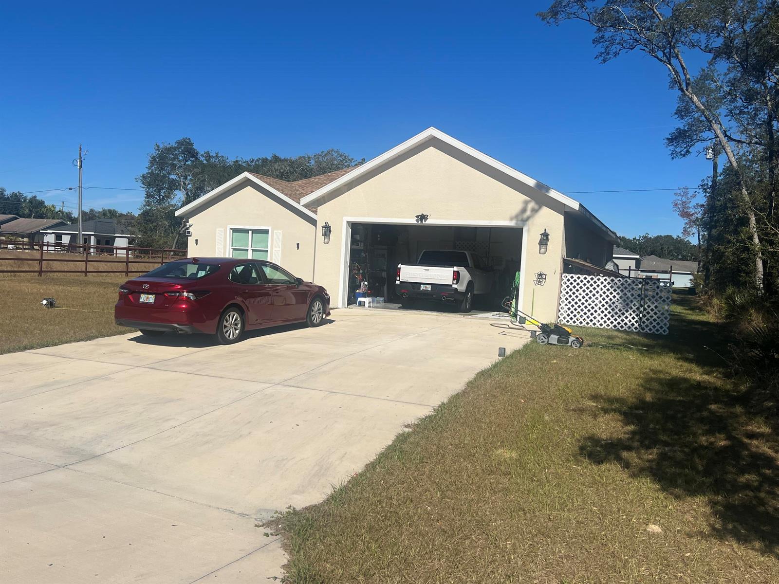 A beige single-story house with a two-car garage, a red sedan, and a white truck — 4009 SW 133rd Loop, Ocala FL 34473, OCALA, FL