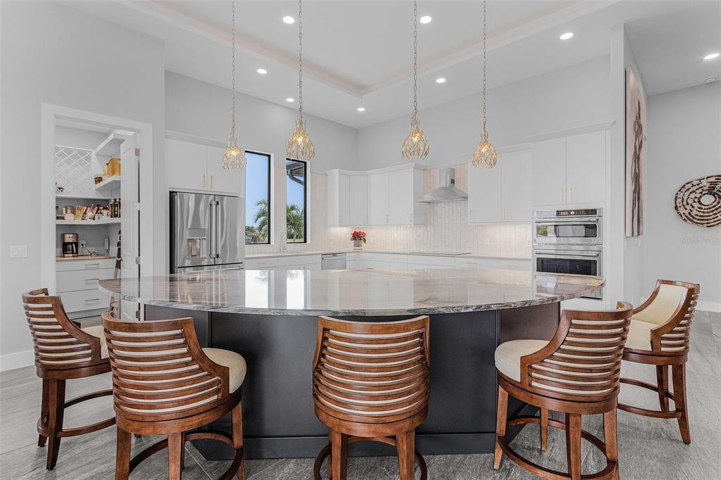 A modern kitchen features a large dark-base island with bar stools and white cabinetry — 1729 NW 41ST AVENUE, CAPE CORAL, FL