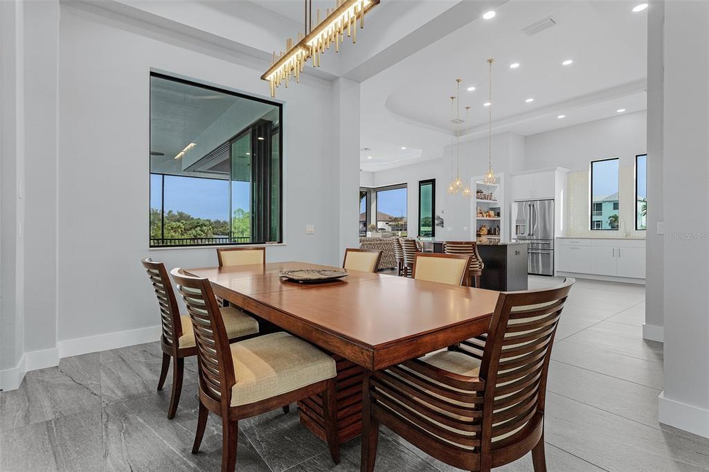 A dining room with a wooden table and chairs leads into an open-concept kitchen — 1729 NW 41ST AVENUE, CAPE CORAL, FL