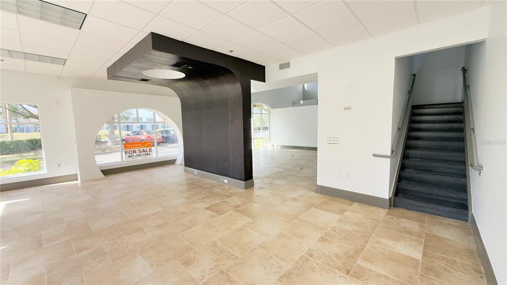 An interior view of a commercial space with tile flooring, a dark curved partition, and stairs — 8803 FUTURES DRIVE UNIT 3, ORLANDO, FL