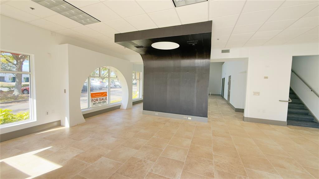 A commercial interior features tan tile flooring, a large black architectural feature, and arched windows — 8803 FUTURES DRIVE UNIT 3, ORLANDO, FL
