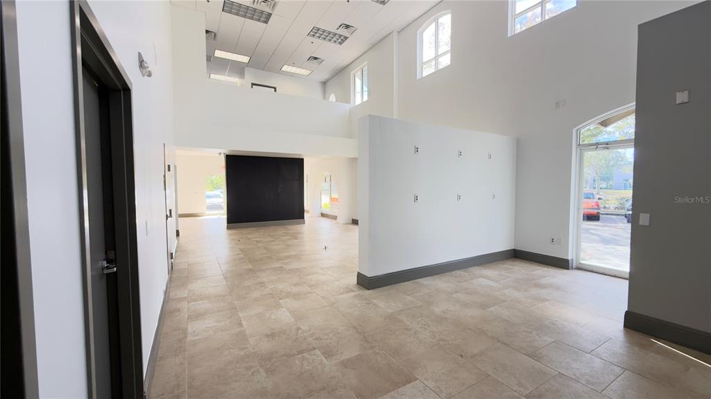 An open commercial space features light tile flooring, a central partition wall, and high ceilings — 8803 FUTURES DRIVE UNIT 3, ORLANDO, FL