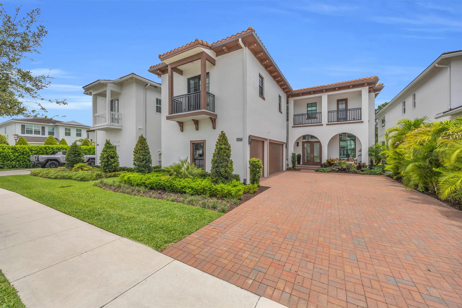 A two-story Mediterranean-style house features a brick driveway, arched entryways, and a balcony — 13372 Bernoulli Way, Palm Beach Gardens FL 33418, PALM BEACH GARDENS, FL