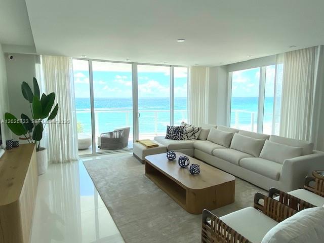A modern living room features a white sofa, wooden coffee table, and ocean views — 3951 S Ocean Dr # 501, Hollywood FL 33019, HOLLYWOOD, FL