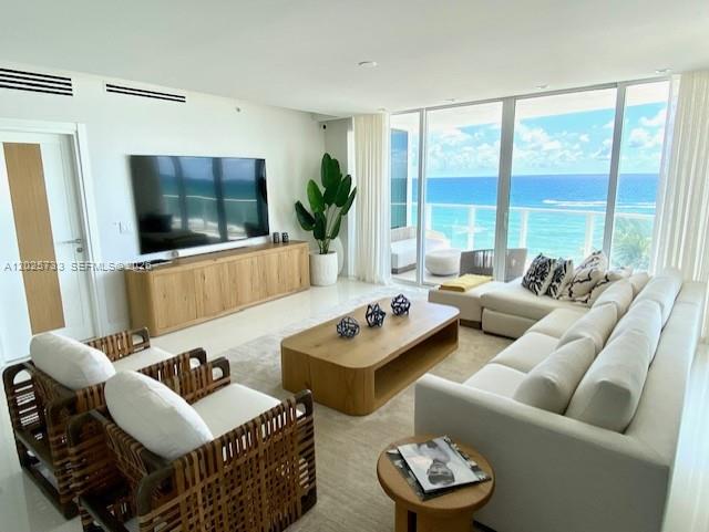 A modern living room features a large television, wooden media console, and ocean views — 3951 S Ocean Dr # 501, Hollywood FL 33019, HOLLYWOOD, FL