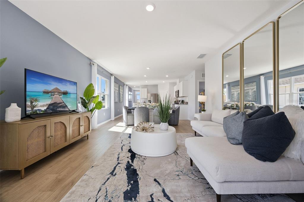 A bright living room features a light-colored sofa, a round coffee table, and a television — 1358 CAMELLIA BLOOM LANE, SANFORD, FL