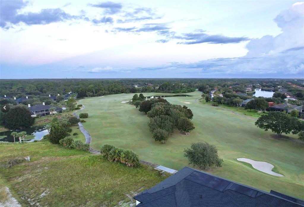 An aerial view shows a golf course fairway with trees, sand traps, and surrounding houses — 455 RIVERFRONT DRIVE UNIT A303, PALM COAST, FL