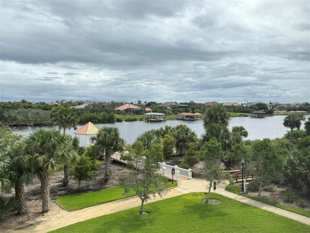 An elevated view of a grassy lawn, a wooden footbridge, and a lake with gazebos — 455 RIVERFRONT DRIVE UNIT A303, PALM COAST, FL