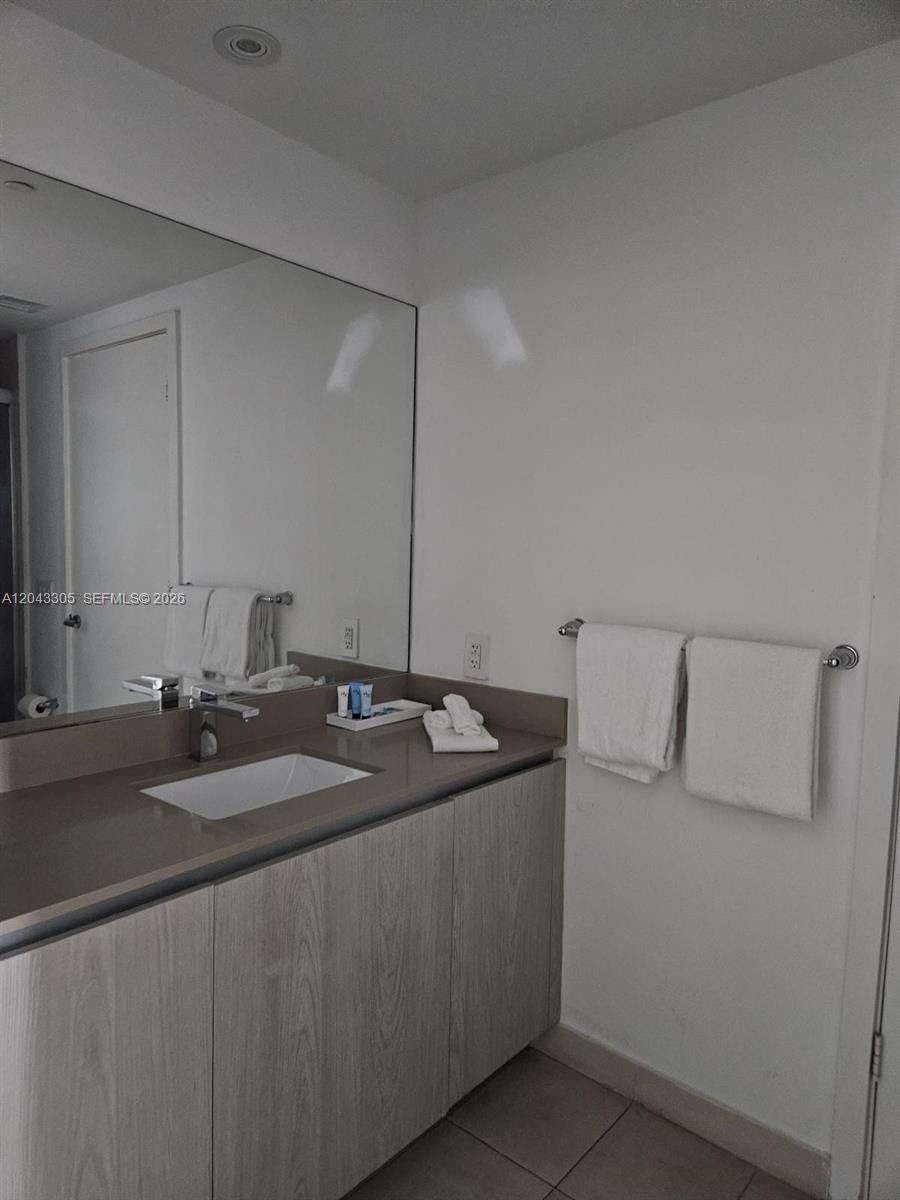 A modern bathroom features a single vanity with a light wood cabinet and mirror — 4111 S Ocean Dr # 1204, Hollywood FL 33019, HOLLYWOOD, FL