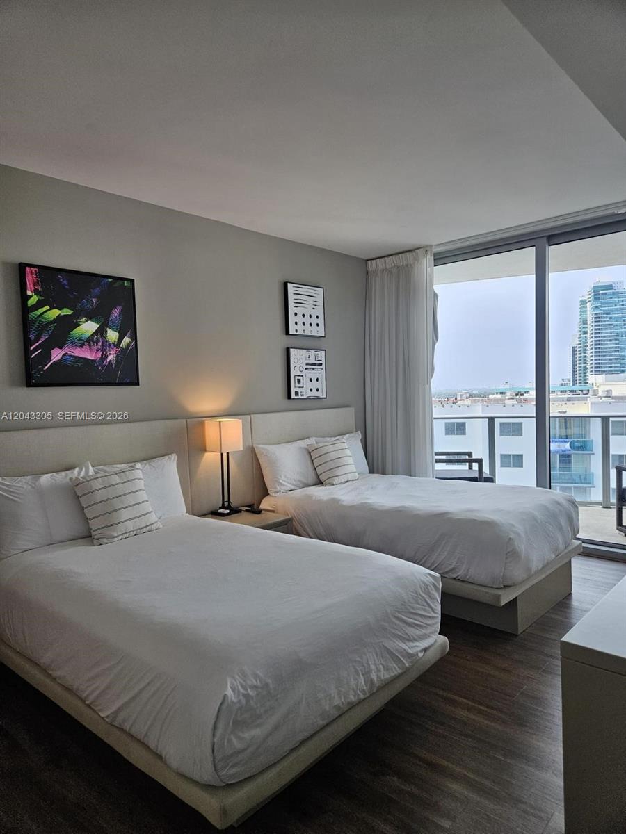 A bedroom features two beds, a nightstand with a lamp, wall art, and a balcony view — 4111 S Ocean Dr # 1204, Hollywood FL 33019, HOLLYWOOD, FL