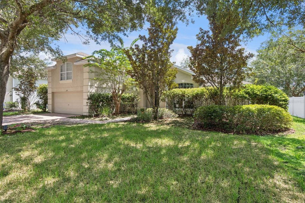 A single-story house with a beige stucco exterior, a two-car garage, and a landscaped yard — 1272 BRAMLEY LANE, DELAND, FL