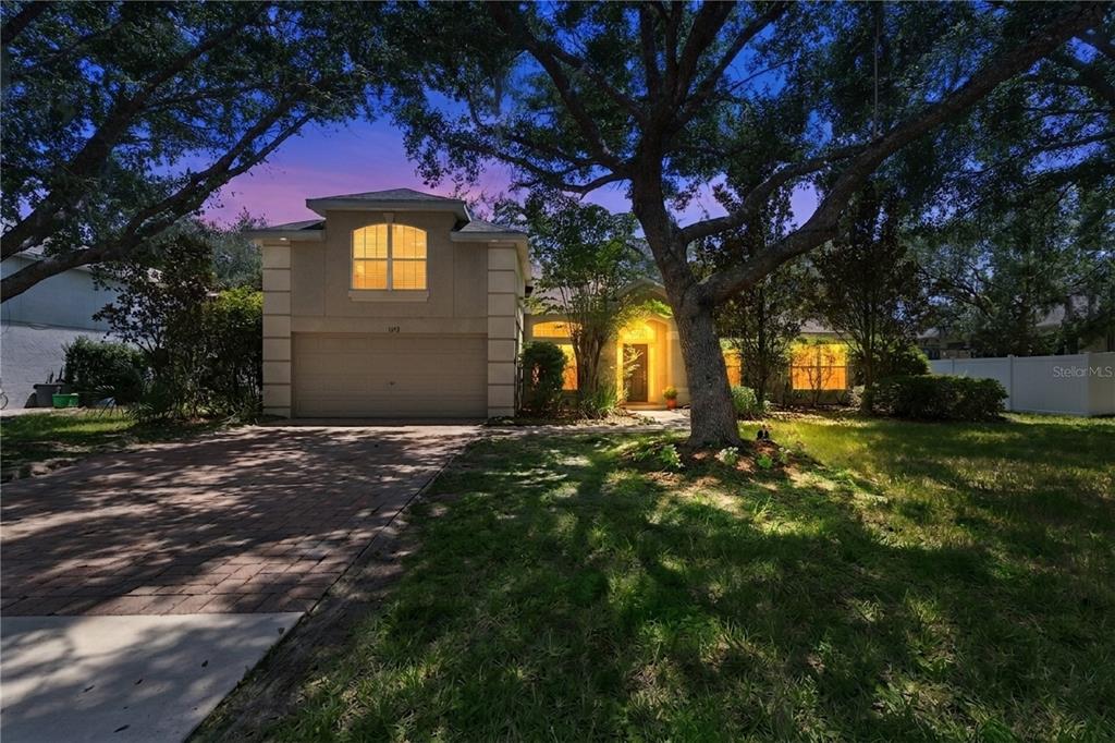 A two-story house with a brick driveway, a garage, and large trees in the front yard — 1272 BRAMLEY LANE, DELAND, FL