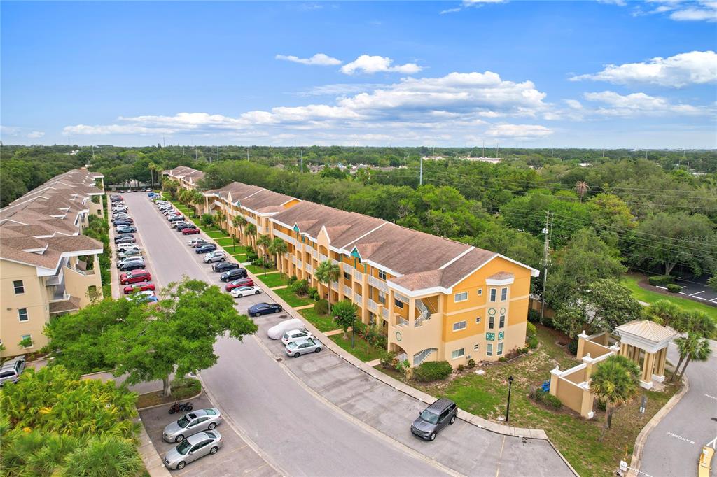 An aerial view shows a multi-story apartment complex with a parking lot and surrounding trees — 2209 UTOPIAN DRIVE E UNIT 307, CLEARWATER, FL
