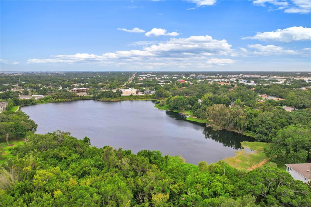 An aerial view shows a lake surrounded by dense trees and nearby residential buildings — 2209 UTOPIAN DRIVE E UNIT 307, CLEARWATER, FL