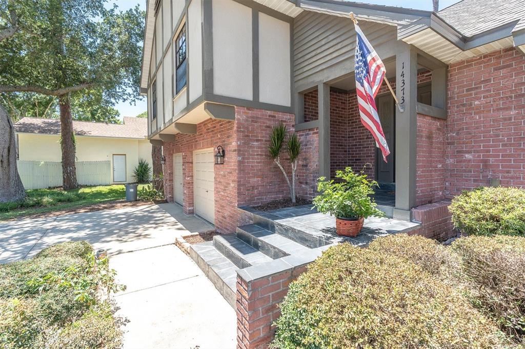 A brick house exterior features a front porch, stone steps, and an American flag — 14373 82ND TERRACE, SEMINOLE, FL