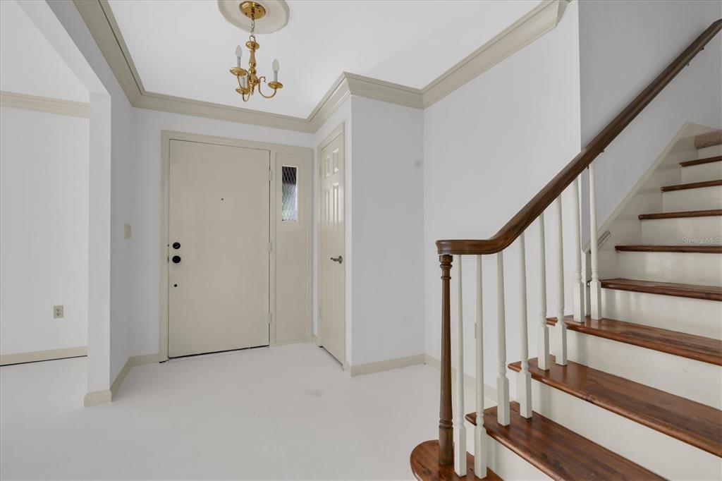 An entryway features white walls, a staircase with wooden treads, and a small chandelier — 14373 82ND TERRACE, SEMINOLE, FL