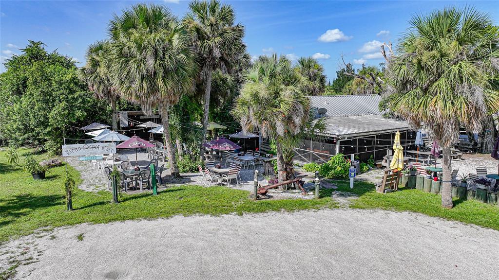 An outdoor patio area with tables, umbrellas, and palm trees at the Bean Depot Cafe — 4370 GARDEN ROAD, PORT CHARLOTTE, FL