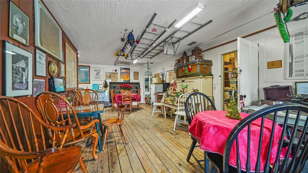 A rustic dining room features wooden floors, multiple tables with chairs, and vintage wall decor — 4370 GARDEN ROAD, PORT CHARLOTTE, FL