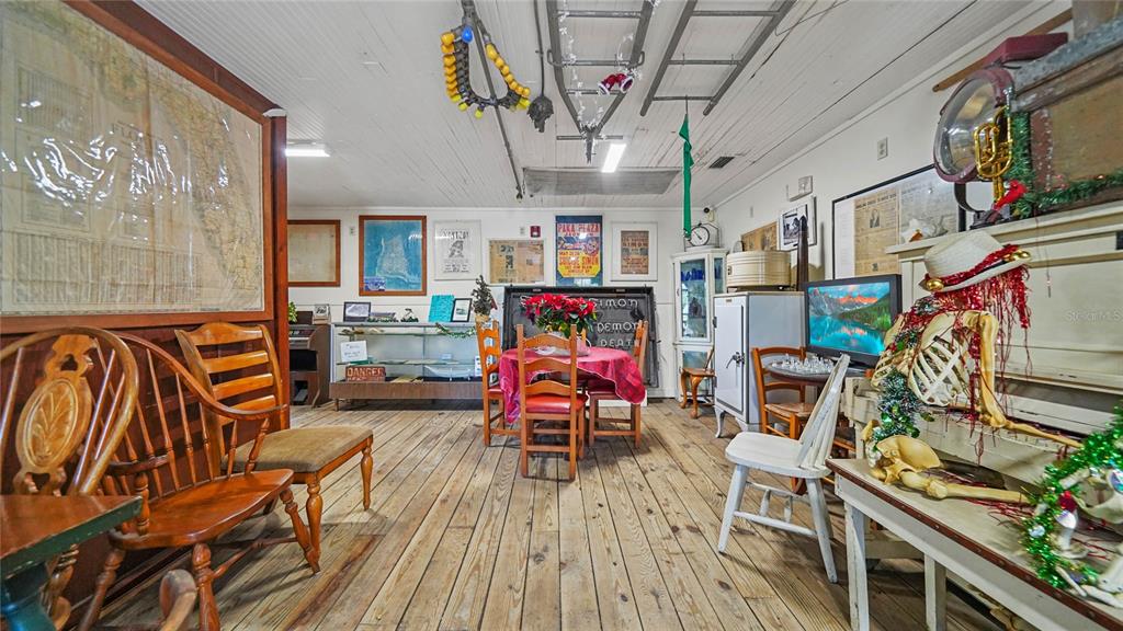 A rustic room with wood floors, a dining set, and eclectic decor including a skeleton — 4370 GARDEN ROAD, PORT CHARLOTTE, FL