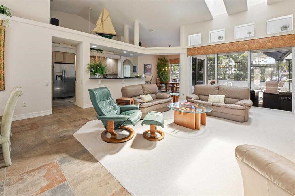 A living room features a vaulted ceiling, tile and carpet flooring, and a glass-topped table — 3267 SUGARLOAF KEY ROAD, PUNTA GORDA, FL