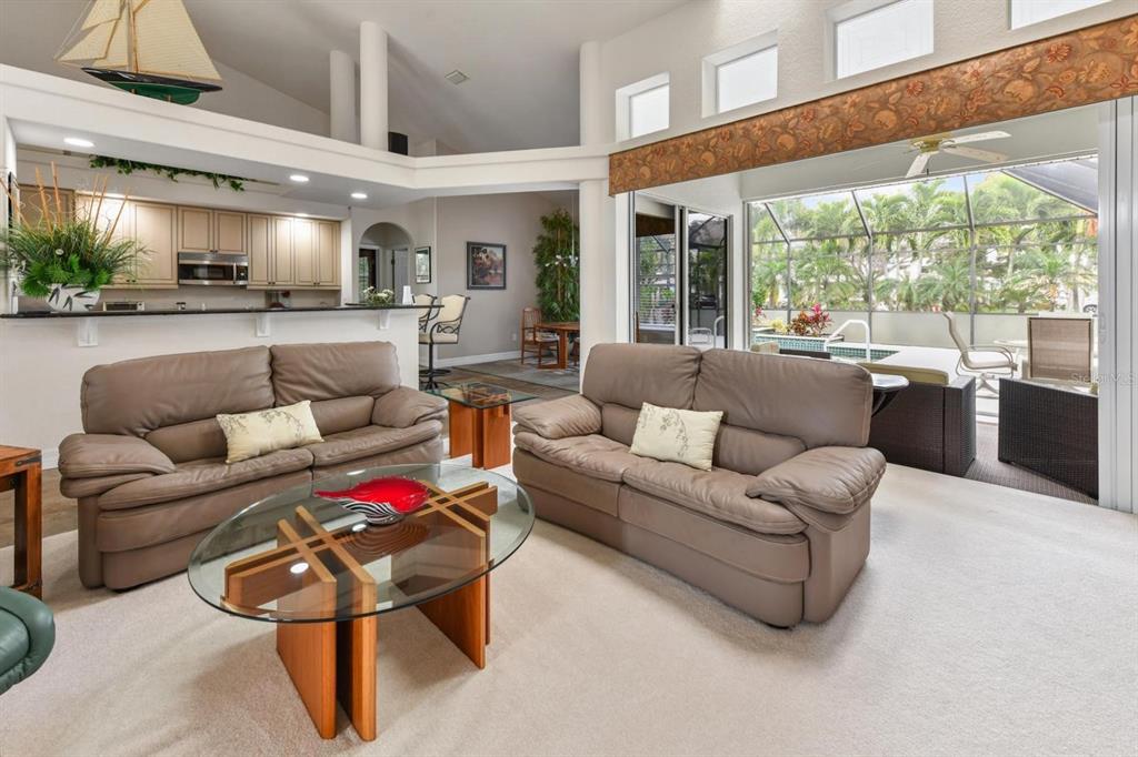 A living room with two leather sofas, a glass coffee table, and a view of a pool — 3267 SUGARLOAF KEY ROAD, PUNTA GORDA, FL