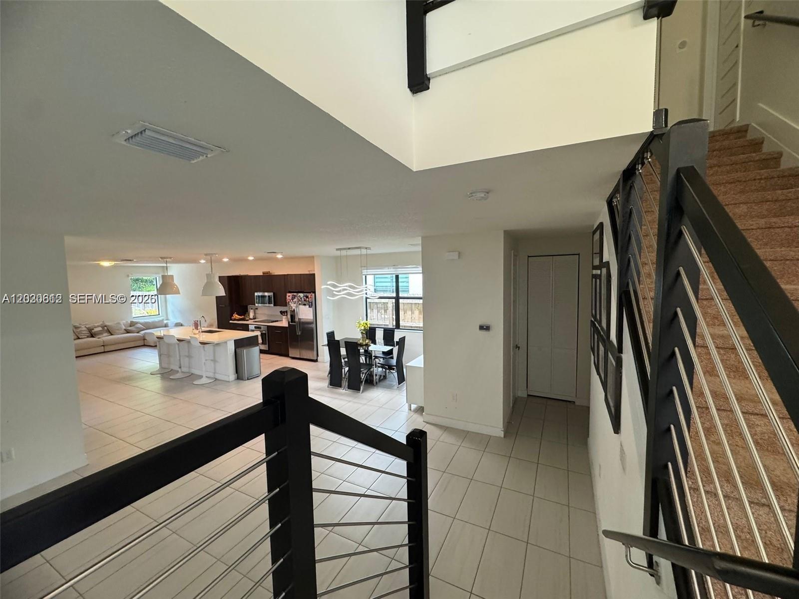 A view from a staircase looking down into an open-concept kitchen and dining area — 10240 NW 76th Ter, Doral FL 33178, DORAL, FL
