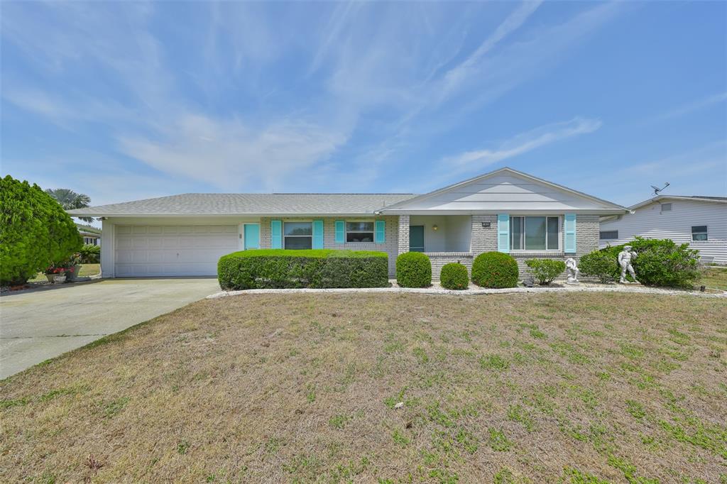 A single-story house with a gray roof, brick exterior, and a two-car garage — 1809 HAVERFORD AVENUE, SUN CITY CENTER, FL