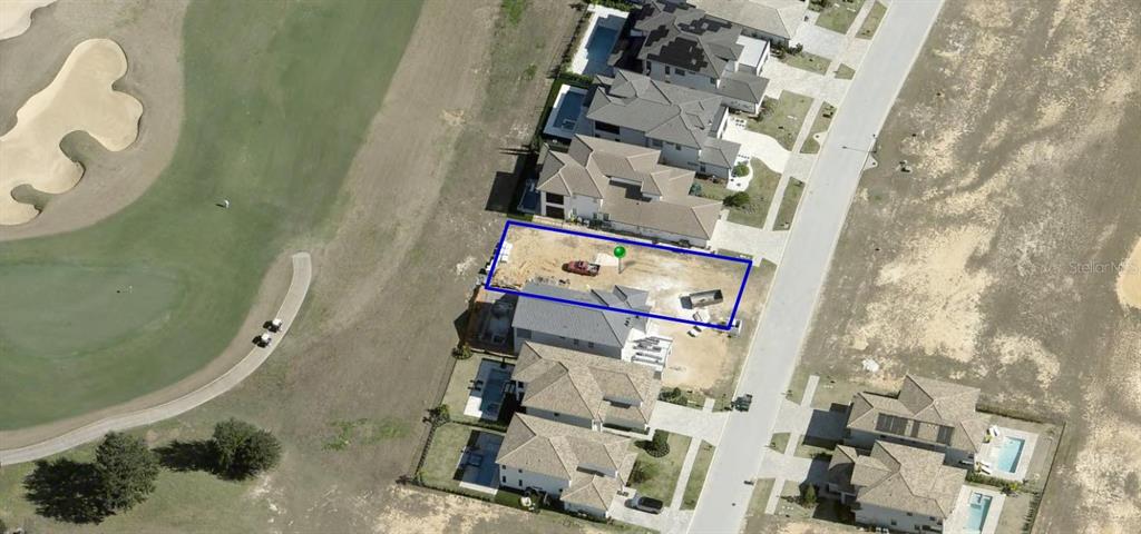 This aerial view shows a vacant residential lot under construction next to a golf course — 15831 VETTA DRIVE, BELLA COLLINA, FL