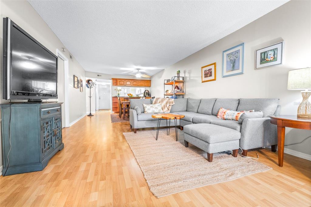 A living room features a gray sectional sofa, a wood coffee table, and hardwood flooring — 90 S HIGHLAND AVENUE UNIT 110, TARPON SPRINGS, FL