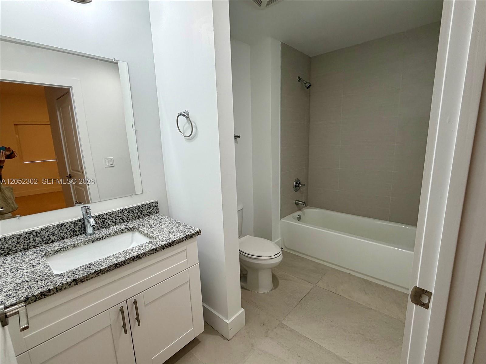 This bathroom features a white vanity with a granite countertop, a toilet, and a tub-shower — 2641 NW 24th Ct # 204, Miami FL 33142, MIAMI, FL