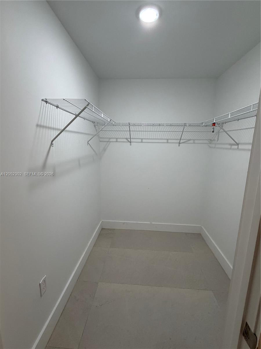A walk-in closet features white walls, tile flooring, and wire shelving — 2641 NW 24th Ct # 204, Miami FL 33142, MIAMI, FL