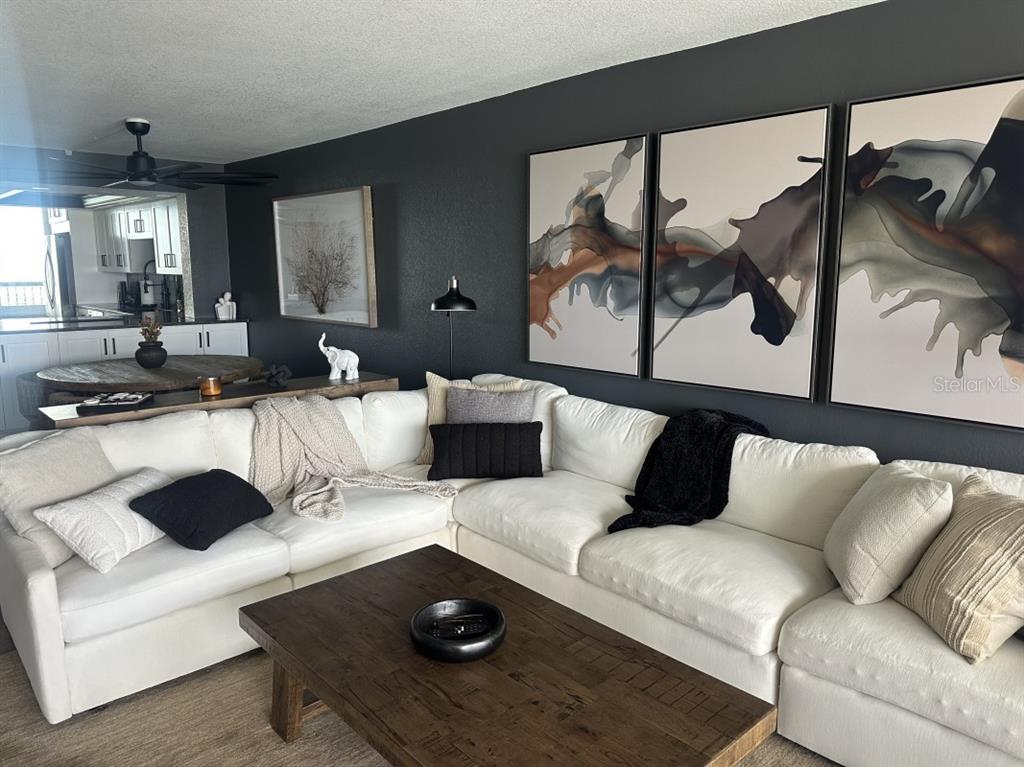 A living room features a white sectional sofa, a dark wood coffee table, and abstract wall art — 9425 BLIND PASS ROAD UNIT 1207, ST PETERSBURG, FL