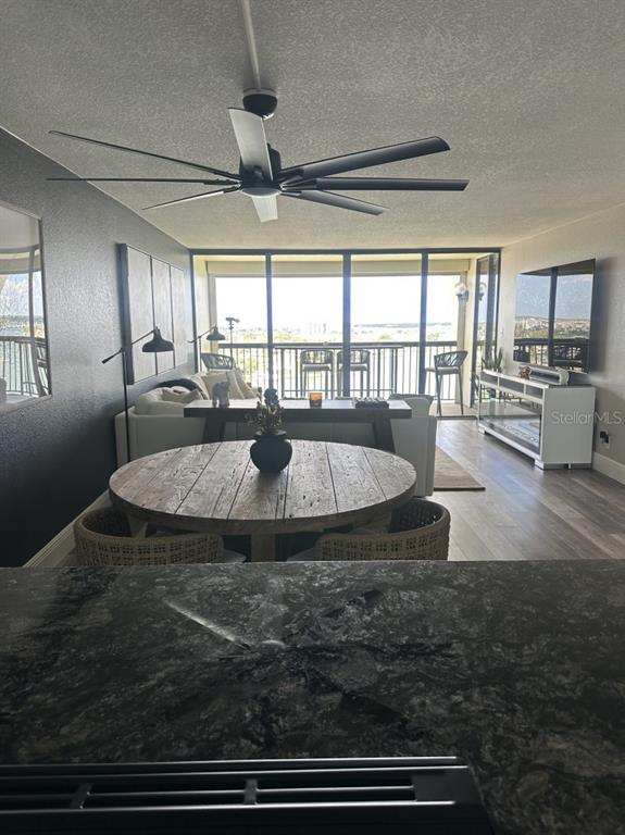 A dining area and living room with a ceiling fan, wood table, and balcony view — 9425 BLIND PASS ROAD UNIT 1207, ST PETERSBURG, FL