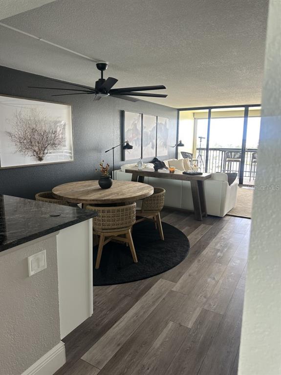 A dining area with a round wooden table sits before a living room and balcony — 9425 BLIND PASS ROAD UNIT 1207, ST PETERSBURG, FL