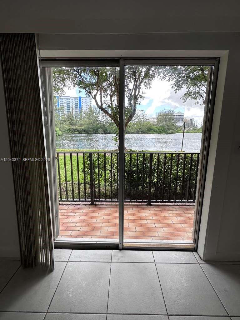 A sliding glass door opens to a tiled balcony overlooking a lake and trees — 4805 NW 7th St # 15, Miami FL 33126, MIAMI, FL