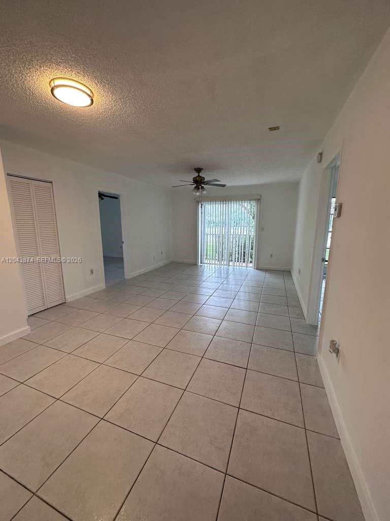 This living room features white walls, tile flooring, a ceiling fan, and sliding glass doors — 4805 NW 7th St # 15, Miami FL 33126, MIAMI, FL