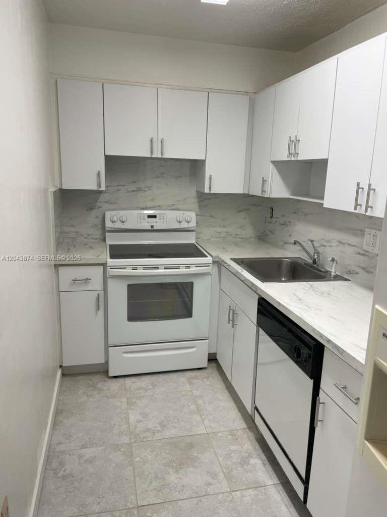 A galley kitchen features white cabinets, marble-look countertops, and white appliances — 4805 NW 7th St # 15, Miami FL 33126, MIAMI, FL