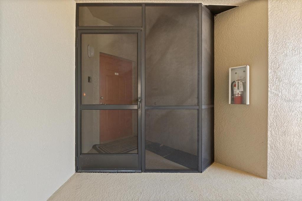 A screen door leads to a red entry door with a fire extinguisher mounted nearby — 7803 GRAND ESTUARY TRAIL UNIT 308, BRADENTON, FL