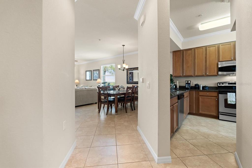 A view from a hallway looking into a dining area and a kitchen with wood cabinets — 7803 GRAND ESTUARY TRAIL UNIT 308, BRADENTON, FL
