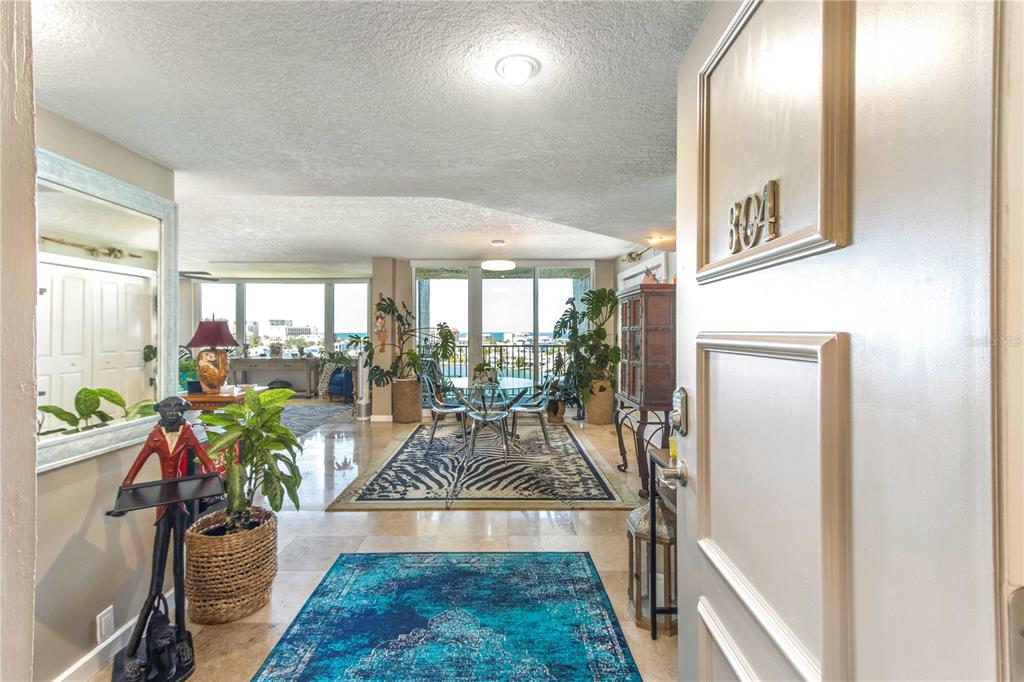 An entryway leads into an open-concept living and dining area with tile floors and ocean views — 736 ISLAND WAY UNIT 804, CLEARWATER, FL
