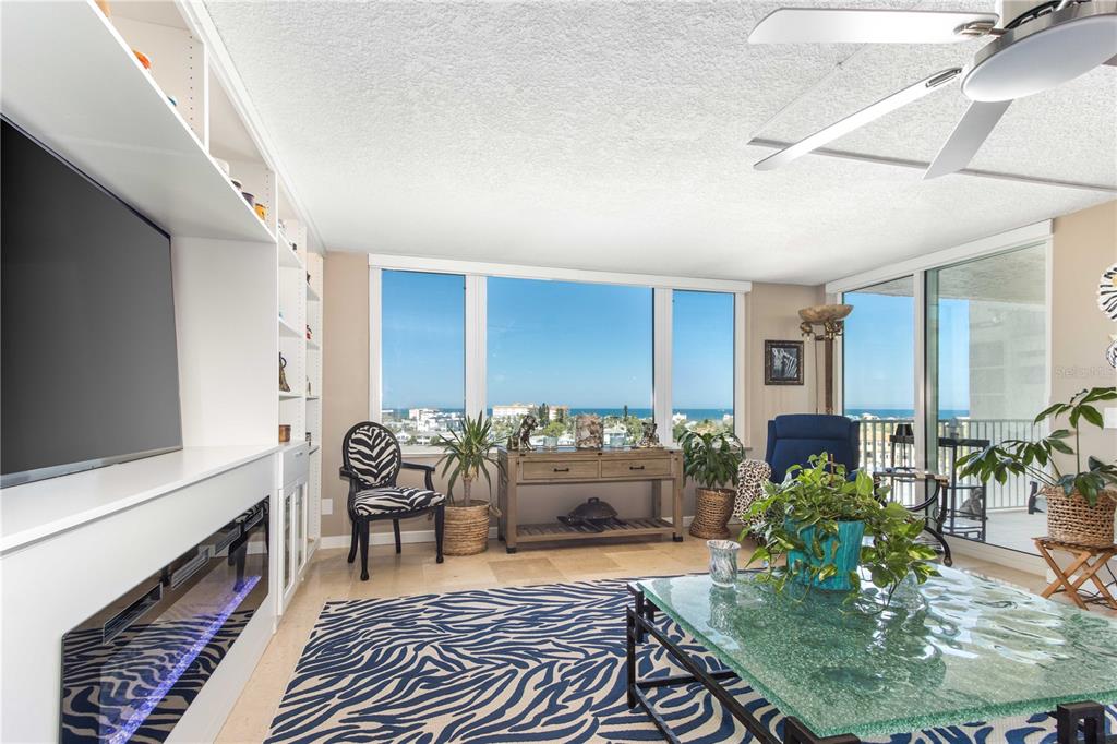 A living room features a zebra-print rug, a glass coffee table, and ocean views — 736 ISLAND WAY UNIT 804, CLEARWATER, FL