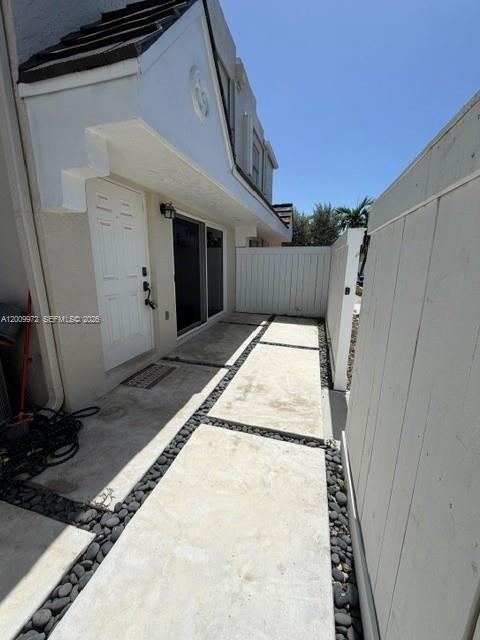 A concrete walkway with stone borders leads to a white door and sliding glass patio door — 4590 SW 68th Ct Cir # 8, Miami FL 33155, MIAMI, FL