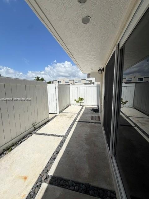A concrete patio features large pavers, a white privacy fence, and a sliding glass door — 4590 SW 68th Ct Cir # 8, Miami FL 33155, MIAMI, FL