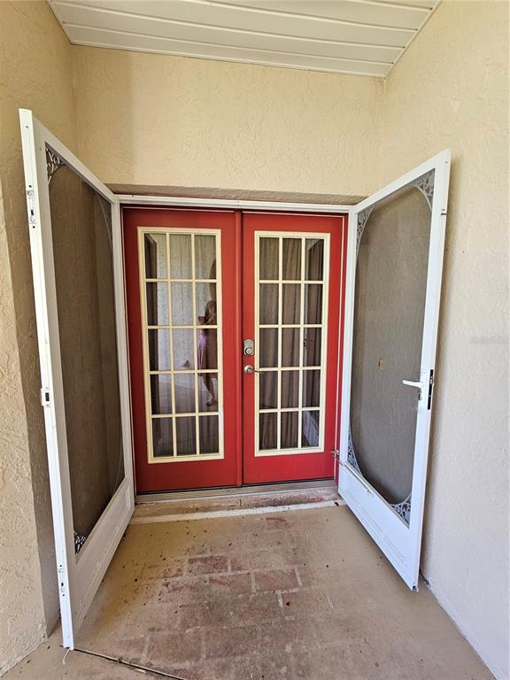 A red double door with glass panes is framed by two open white screen doors — 17817 SE 115TH COURT, SUMMERFIELD, FL