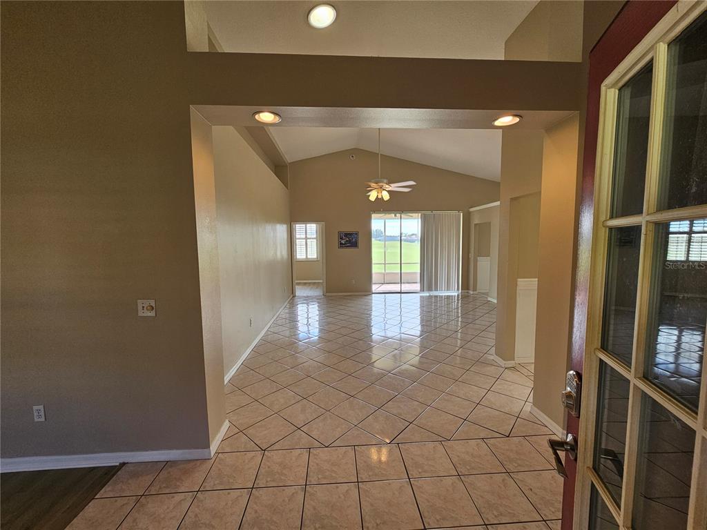 An entryway leads into a tiled living area with a vaulted ceiling and sliding glass doors — 17817 SE 115TH COURT, SUMMERFIELD, FL