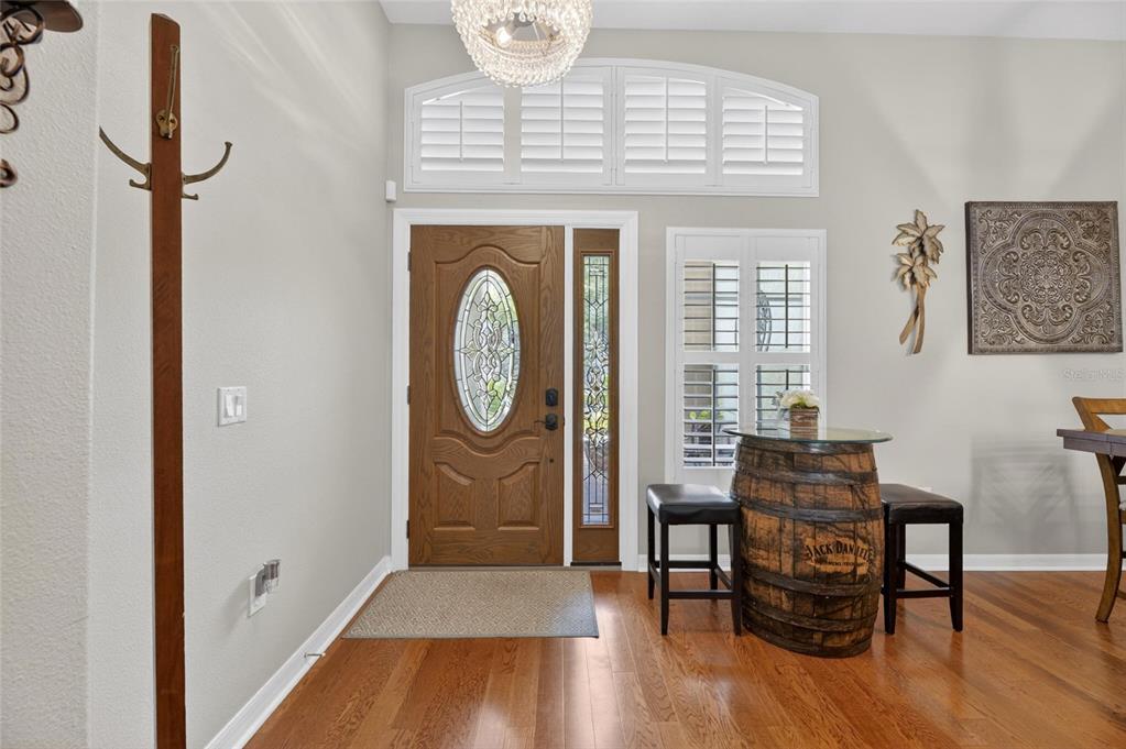 An entryway features a wooden front door, hardwood floors, and a barrel-style bistro table — 18116 KARA CT, TAMPA, FL